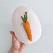 Cargar imagen en el visor de la galería, A hand holding a light pink, paper mache egg box. A spun cotton carrot adorns the cover. Pic 8 of 12. 
