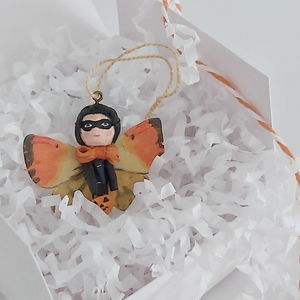 A spun cotton Halloween butterfly girl laying in a white gift box on white shredded tissue paper. Pic 4 of 7. 