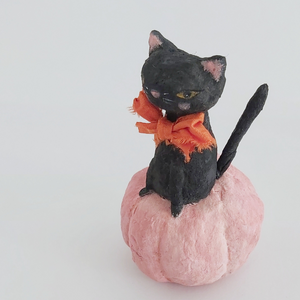 A closer side view of a vintage style spun cotton black cat sitting in a pink pumpkin, against a white background. Pic 3 of 7. 