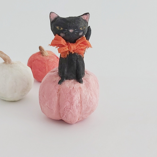 A vintage style spun cotton black cat sitting in a pink pumpkin. White and orange spun cotton pumpkins sit in the background, against a white background. Pic 1 of 7. 