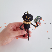 Load image into Gallery viewer, A vintage style, spun cotton black pumpkin man ornament held in hand over Halloween confetti on a white background. Pic 2 of 7. 
