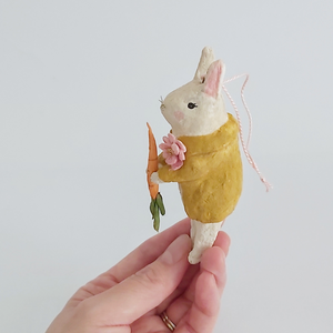 A side view of a vintage style spun cotton bunny ornament, held in hand against a white background. Pic 5 of 12. 