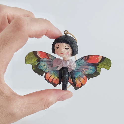 A vintage style spun cotton butterfly girl held in hand against a white background. Pic 1 of 1. 
