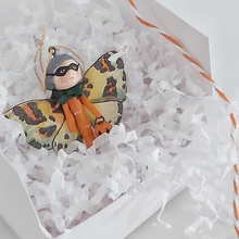 Cargar imagen en el visor de la galería, A spun cotton Halloween butterfly girl laying in a white box on white shredded tissue paper. Pic 6 of 7. 
