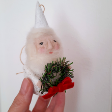 Load image into Gallery viewer, A spun cotton gnome holding a green wreath with a red bow, held by a hand against a light background.

