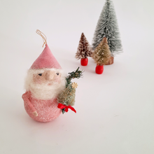 Load image into Gallery viewer, Decorative gnome in a pink outfit holding a small bottle brush tree, set against a white background with miniature trees.
