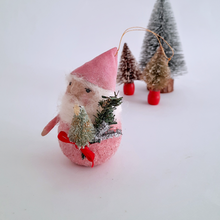Load image into Gallery viewer, A spun cotton gnome with a pink hat  holding a small tree, with miniature trees in the background on a white surface.
