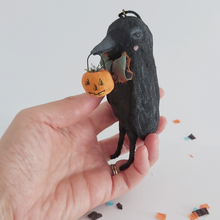 Cargar imagen en el visor de la galería, Another view of a vintage style spun cotton crow ornament, sitting in a hand against a white background over Halloween confetti. Pic 5 of 8. 
