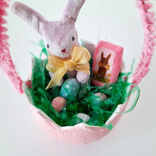 Load image into Gallery viewer, A close-up of a pink egg-shaped basket with green grass, Easter eggs, and a spun cotton bunny on a white background.
