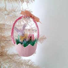 Load image into Gallery viewer, Decorative Easter egg ornament with a  spun cotton bunny, eggs, and boxed chocolate bunny inside, hanging on a white Christmas tree.

