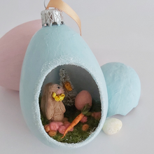Cargar imagen en el visor de la galería, A vintage style spun cotton Easter bunny diorama ornament sitting next to pink and blue eggs against a white background. Pic 1 of 8. 
