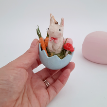 Load image into Gallery viewer, A hand holding a vintage style, spun cotton Easter bunny ornament against a white background. A pink egg sits in the distance. Pic 2 of 8. 
