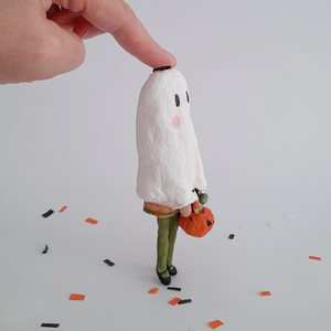 A side view of a vintage style, spun cotton ghost girl ornament on Halloween confetti against a white background. Pic 6 of 8. 