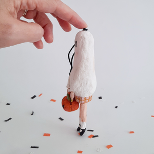 A side view of a vintage style, spun cotton ghost girl ornament over Halloween confetti against a white background. Pic 6 of 8. 