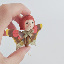 Load image into Gallery viewer, A closer view of spun cotton ginger butterfly girl, held in hand against a white background. Pic 2 of 7. 
