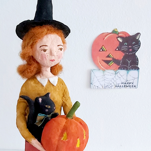 A vintage style, spun cotton Halloween girl art doll closeup with a Halloween greeting in the background. Pic 1 of 7.