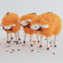Load image into Gallery viewer, A close view of three, vintage style spun cotton needle felted orange sheep. They stand on Halloween confetti, against a white background. Pic 4 of 5. 
