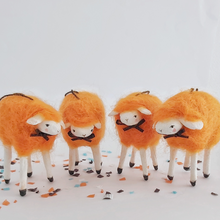 Load image into Gallery viewer, A close view of four vintage style, spun cotton needle felted orange sheep ornaments. They stand on Halloween confetti, against a white background. Pic 1 of 5. 
