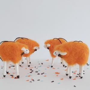 A side view of 4 orange, spun cotton needle felted sheep ornaments. Pic 5 of 5. 