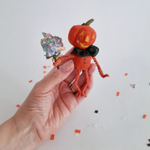 Cargar imagen en el visor de la galería, Another photo of a vintage style, spun cotton pumpkin man held in a hand over Halloween confetti  on a white background. Pic 2 of 8. 
