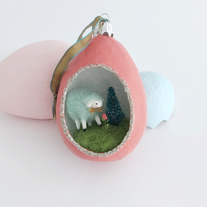 A vintage style spun cotton sheep diorama ornament sitting against pink and blue egg ornaments on a white background. Pic 3 of 6. 
