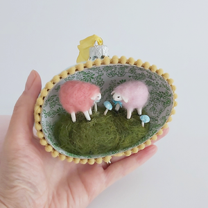 A vintage style spun cotton sheep egg diorama ornament held in a hand against a white background. Pic 3 of 6. 