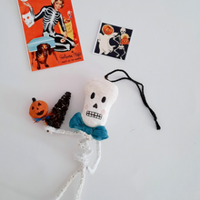 Load image into Gallery viewer, A vintage style, spun cotton pipe cleaner skeleton laying next to vintage skeleton illustrations. Pic 2 of 4.
