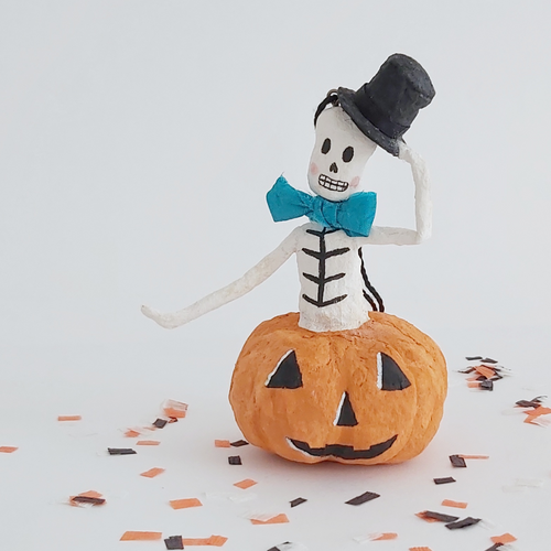 A vintage style, spun cotton skeleton in a jack-o-lantern sitting on Halloween confetti. Pic 1 of 7. 