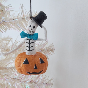 A vintage style, spun cotton skeleton in a jack-o-lantern hanging from a tree. Pic 3 of 7. 