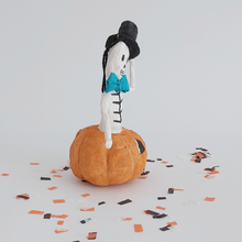 Load image into Gallery viewer, A side view of a vintage style, spun cotton skeleton in a jack-o-lantern on Halloween confetti. Pic 6 of 7. 
