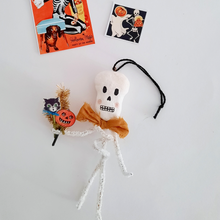 Load image into Gallery viewer, A vintage style, spun cotton pipe cleaner skeleton ornament laying by two vintage skeleton illustrations. Pic 4 of 4. 
