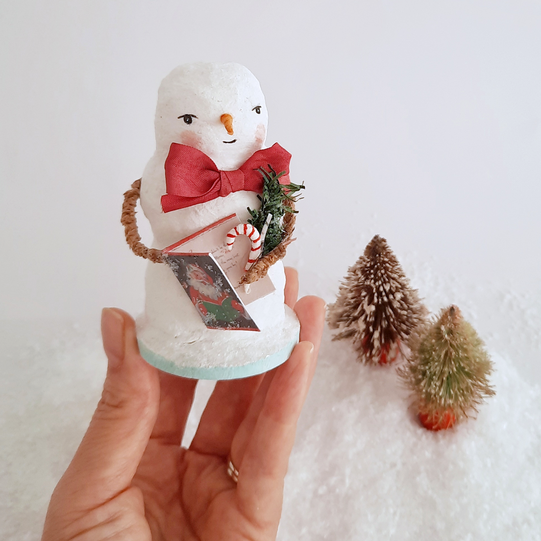 A hand holding a vintage style, spun cotton snowman against a white background, next to two vintage bottlebrush trees. Pic 1 of 6. 