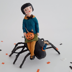 A photo of a vintage style, spun cotton girl sitting on a spun cotton spider against a white background on Halloween confetti. Pic 4 of 10. 