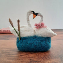 Load image into Gallery viewer, A spun cotton swan sculpture with a blue felted base on a wooden surface.

