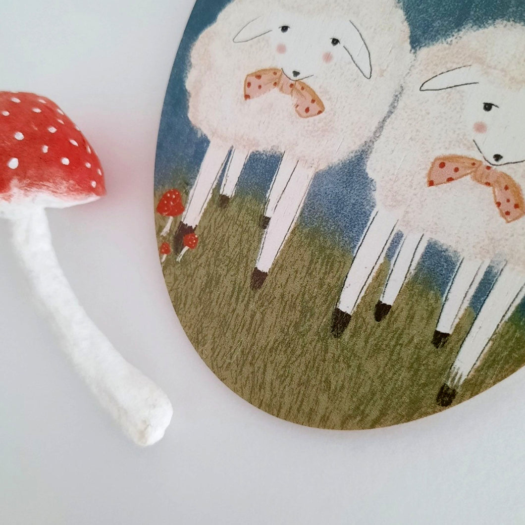 A close-up photo of a wooden sheep ornament next to a spun cotton mushroom ornament. Pic 1 of 6. 