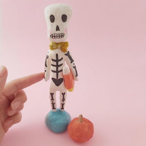 Full shot of spun cotton skeleton, holding candy corn. Photo 2