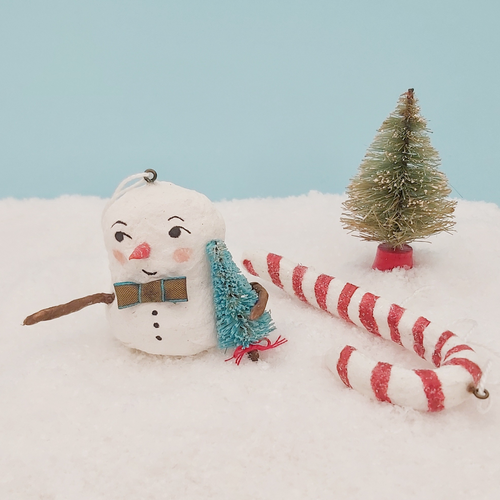 Spun cotton snowman holding bottlebrush tree sitting next to spun cotton candy cane ornament. Pic 1 of 7.