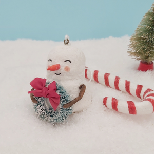 Another closer view of spun cotton snowman holding bottlebrush wreath. Pic 5 of 7. 
