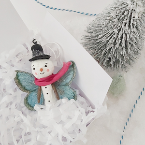 Spun cotton snowman butterfly ornament, laying in white gift box with white tissue shredding. Pic 4 of 5. 