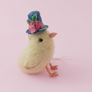 Yellow needle felted chick wearing blue spun cotton top hat with flowers, side view, sitting (picture 2)