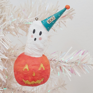 Spun cotton ghost in jack o' lantern ornament, hanging from tree. Pic 2 of 5.