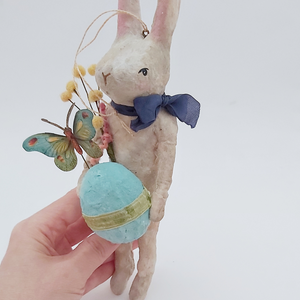 A hand holding a vintage style spun cotton Easter bunny ornament, against a white background. Pic 9 of 9.