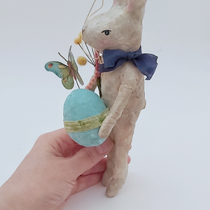 Side view of vintage style, spun cotton Easter bunny ornament held in hand against a white background. Pic 6 of 9.
