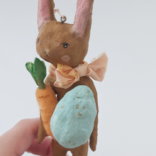 Cargar imagen en el visor de la galería, Close up of spun cotton chocolate brown bunny, holding light blue egg and felted carrot. Pic 2 of 8.
