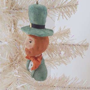Side view of spun cotton leprechaun ornament, hanging from white tree. Pic 4 of 7.