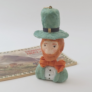 Spun cotton leprechaun ornament, sitting next to vintage Ireland souvenir booklet. Pic 6 of 7.