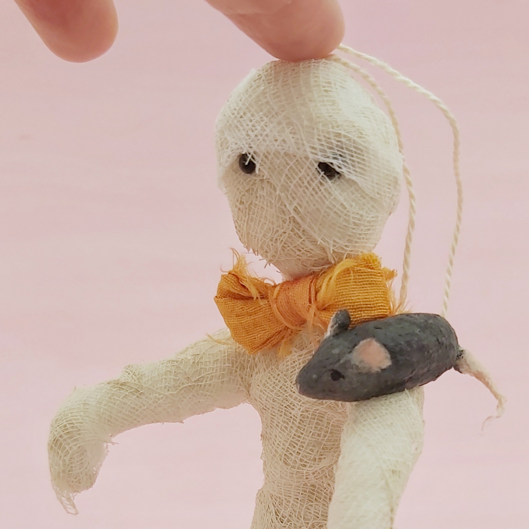 Close up of spun cotton mummy and mouse ornament, on light pink background, being held up by hand. Pic 1 of 8. 