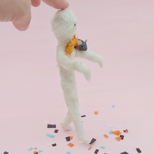 Cargar imagen en el visor de la galería, Opposite side view of spun cotton mummy and mouse ornament, standing on Halloween confetti while being supported by hand. Pic 8 of 8. 
