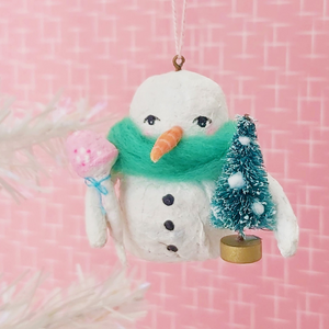 Spun cotton snowman holding bottle brush tree and mushroom. Hanging from thread. 