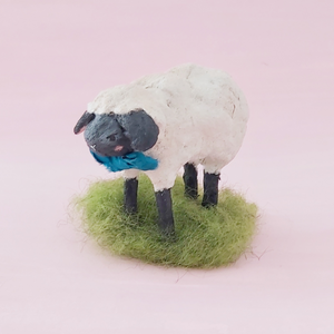 A miniature spun cotton sheep standing on green wool grass, against a pink background. Pic 5 of 8.